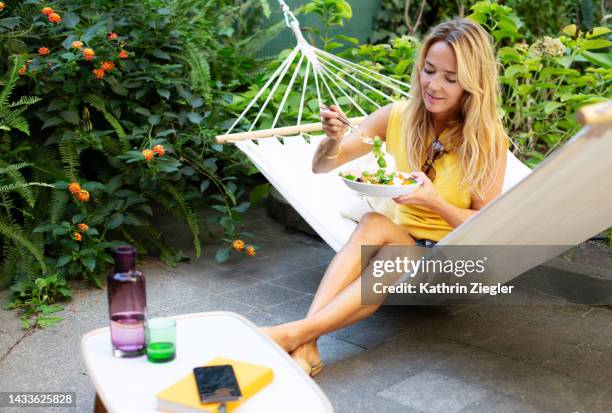 woman sitting in hammock, enjoying fresh salad - salladsskål bildbanksfoton och bilder