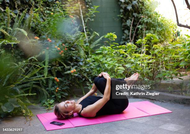 woman stretching on exercise mat in the garden - crecimiento estirón fotografías e imágenes de stock