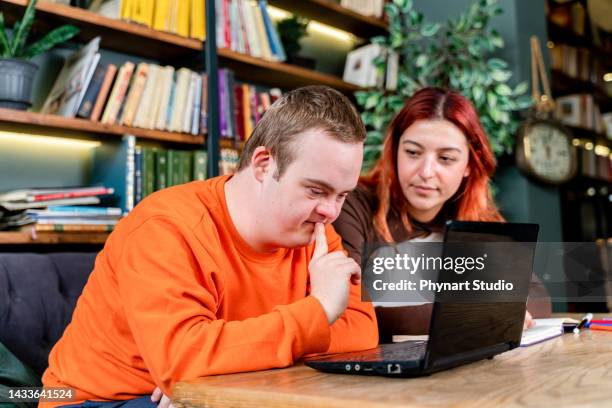 young man with down syndrome and his tutor studying indoors - disability computer stock pictures, royalty-free photos & images
