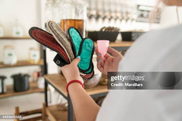 woman comparing different reusable period products, pads and menstrual cups - knie en elleboogbeschermers stockfoto's en -beelden
