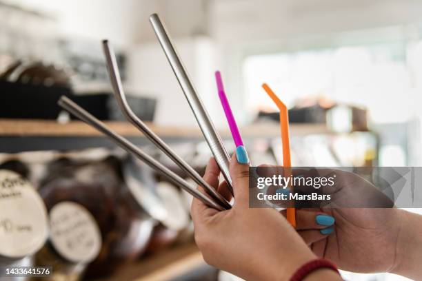 woman holding, comparing reusable drinking straws in zero waste store - metal straw stock pictures, royalty-free photos & images