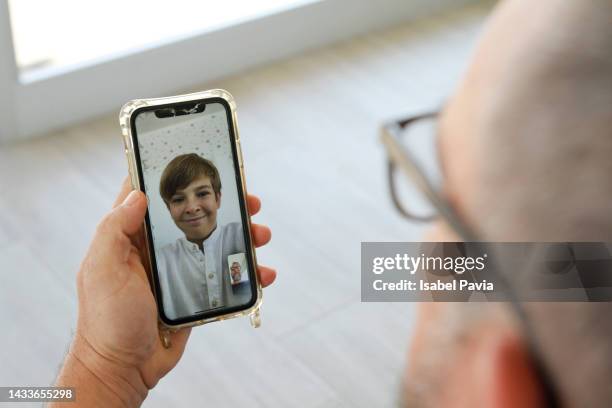 father making videoconference on smartphone with son - modern family media call stockfoto's en -beelden