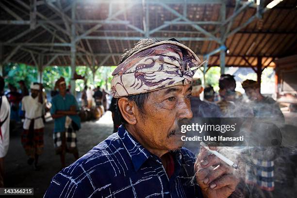 Balinese man smokes during the sacred 'Aci Keburan' ritual at Nyang Api Temple on February 13, 2012 in Gianyar, Bali, Indonesia. Cockfighting in...