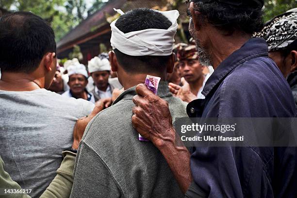 Balinese man holds money during the sacred 'Aci Keburan' ritual at Nyang Api Temple on February 12, 2012 in Gianyar, Bali, Indonesia. Cockfighting in...