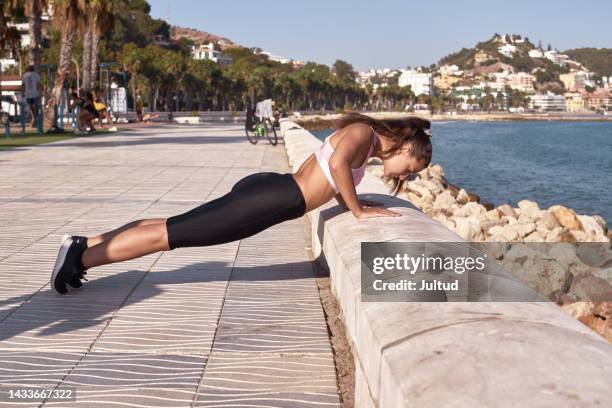 young sportswoman does push-ups in a public park - flexiones fotografías e imágenes de stock