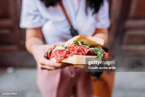 comer sándwich de focaccia casera orgánica en la calle - panini fotografías e imágenes de stock