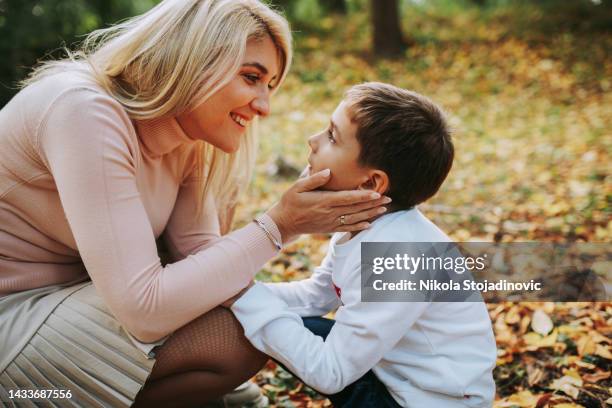 mom and son enjoy autumn - nuzzling stockfoto's en -beelden