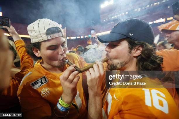 Tennessee Volunteers fans celebrate a win over the Alabama Crimson Tide on the field with cigars at Neyland Stadium on October 15, 2022 in Knoxville,...