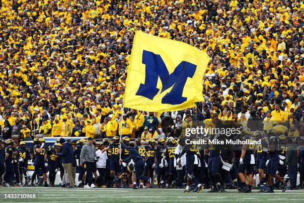 Cheerleader runs a Michigan Wolverines flag up the field after a touchdown during a game against the Penn State Nittany Lions at Michigan Stadium on...