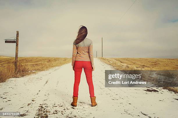 woman standing on snowy contry road - contry road stock pictures, royalty-free photos & images