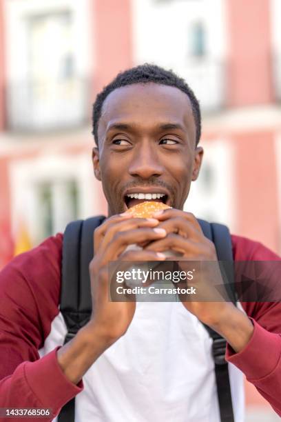 cheerful man eating a hamburger - tentempié stock pictures, royalty-free photos & images