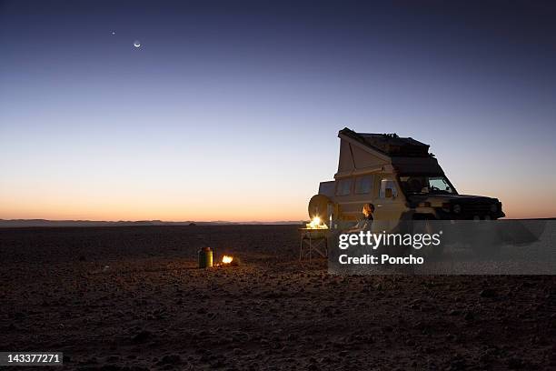 woman sitting in the desert in front of a car - distant fire stock pictures, royalty-free photos & images