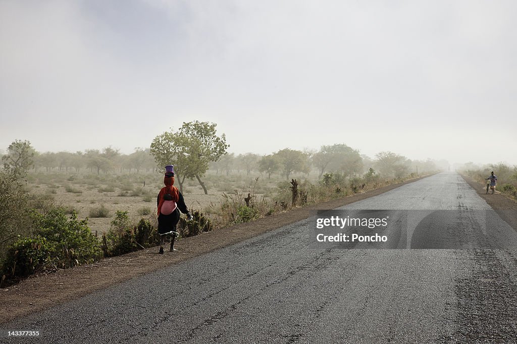 Woman walking beside a road