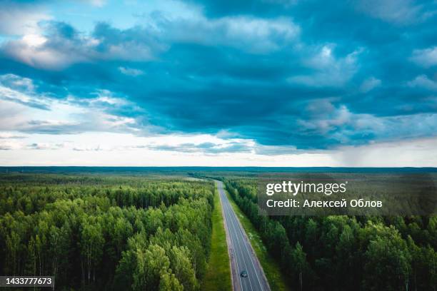 asphalt road under the clouds. top view of the road through the green summer forest - glory road ストックフォトと画像