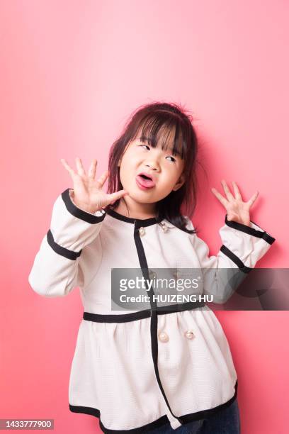 close-up portrait of pretty little girl showing tongue having fun fooling isolated over pink color background - charming stockfoto's en -beelden