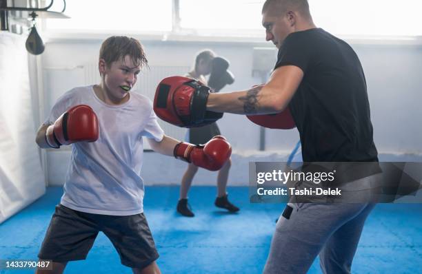 group of kids practicing with instructor boxing at gym - kid boxing stock pictures, royalty-free photos & images