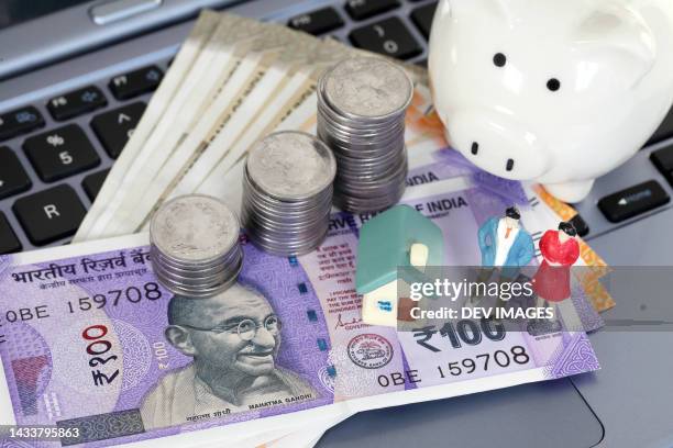 indian currency,  piggy bank and model house on laptop keyboard - gandhi stock-fotos und bilder