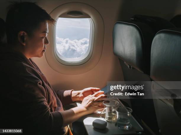 mujer china asiática usando un teléfono inteligente sentada en el asiento de la ventana del pasajero en el avión - aircraft wifi fotografías e imágenes de stock