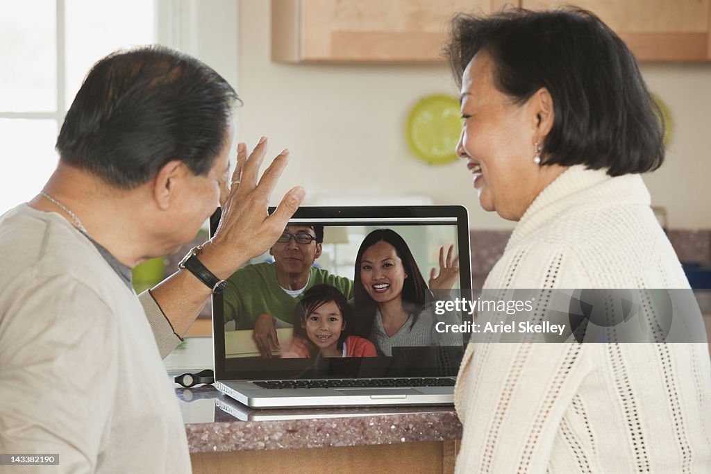 Asian couple talking to family on laptop