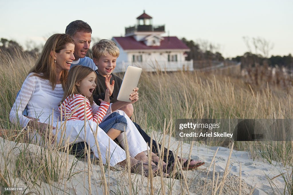 Caucasian family using digital tablet on beach
