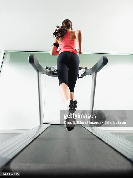 mixed race woman running on treadmill - laufband stock-fotos und bilder