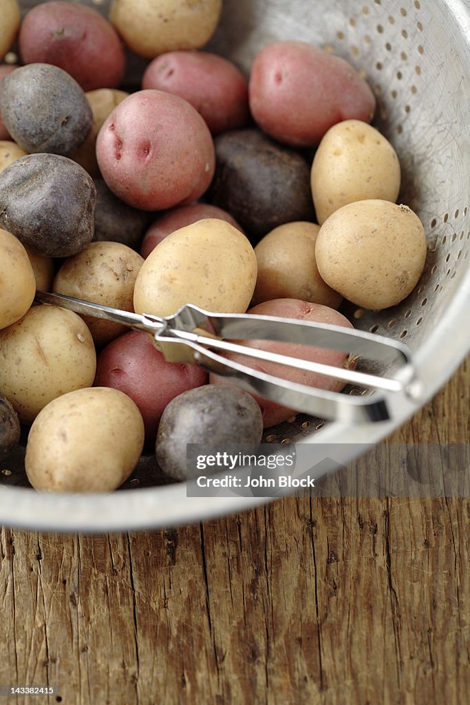 Peeler in colander with multicolored potatoes