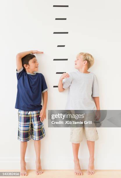 boys measuring themselves against marks on wall - child's wall height stock-fotos und bilder