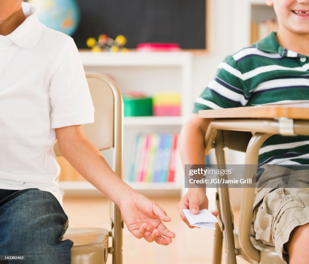 Boys passing note in classroom