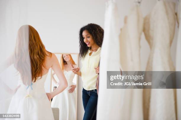 woman helping friend try on wedding dress - anprobekabine stock-fotos und bilder