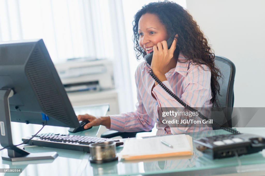 Hispanic businesswoman talking on telephone at desk