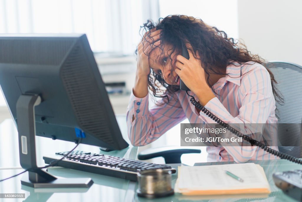 Hispanic businesswoman talking on telephone at desk