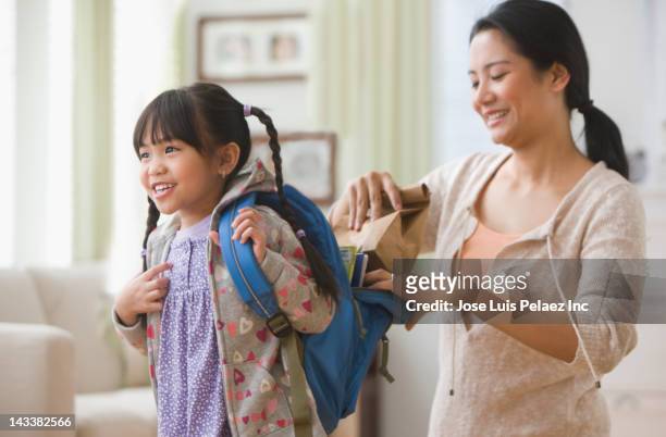 asian mother helping daughter get ready for school - packing kids backpack stockfoto's en -beelden