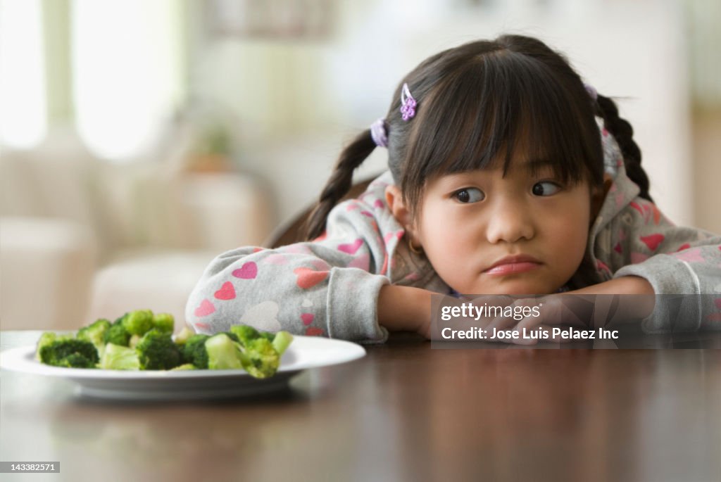 Asian girl looking at broccoli