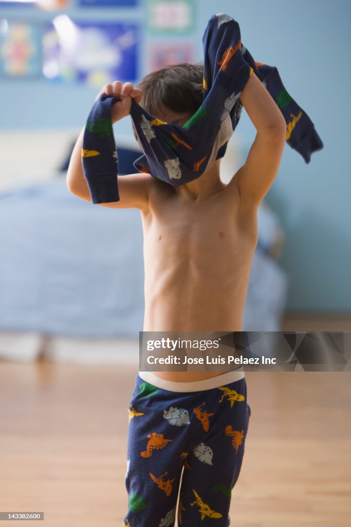 Mixed race boy putting on pajamas