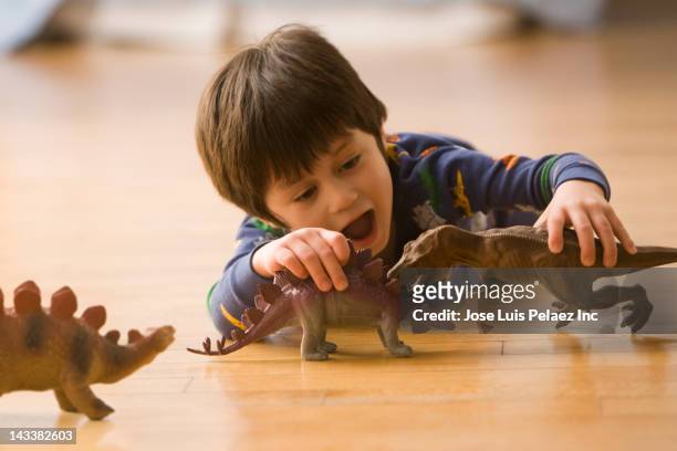 mixed race boy playing with dinosaur toys - dinosaur toy i stock pictures, royalty-free photos & images