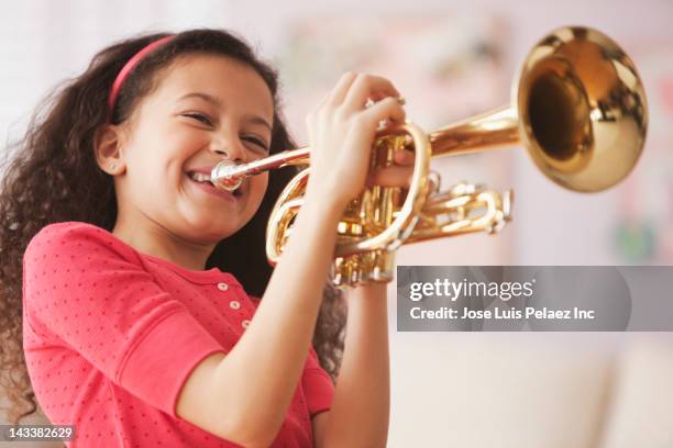 hispanic girl playing trumpet - children holding musical instruments stock pictures, royalty-free photos & images