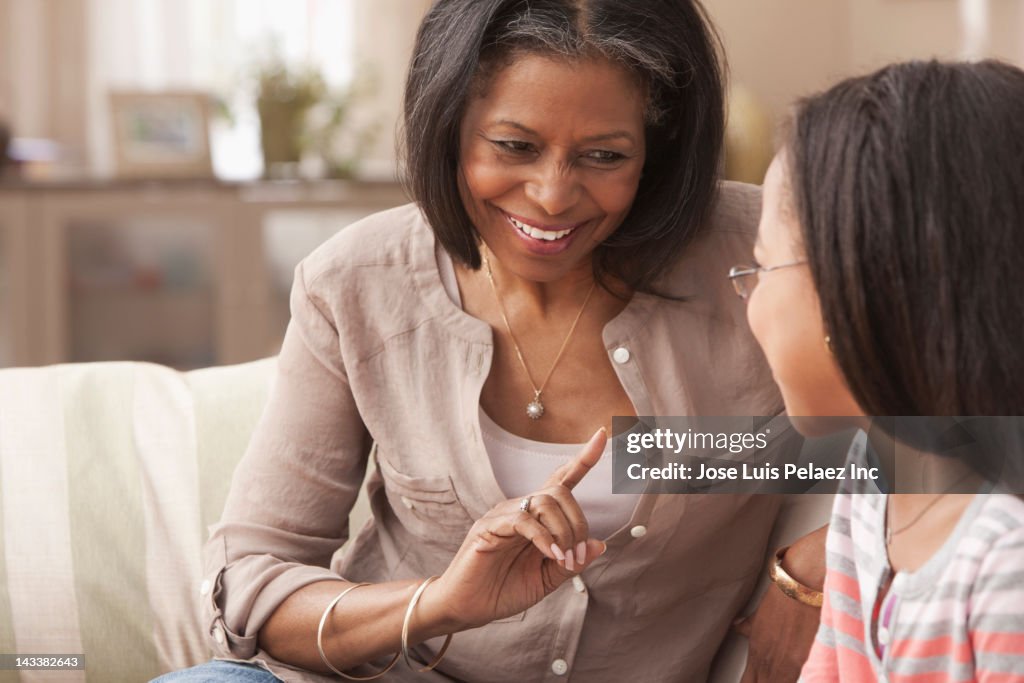 African American grandmother and granddaughter talking on sofa