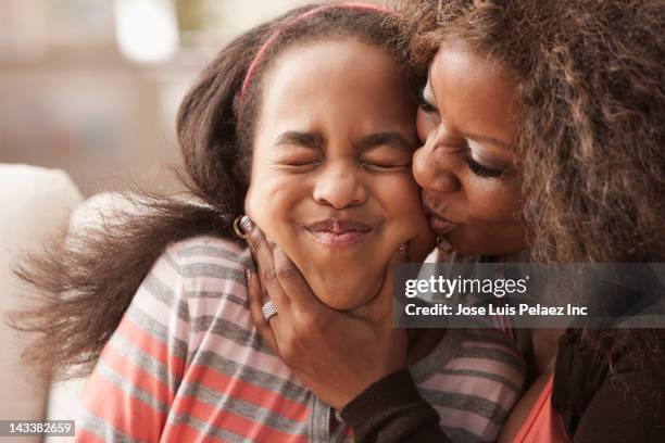 african american mother kissing daughter - squeezing imagens e fotografias de stock