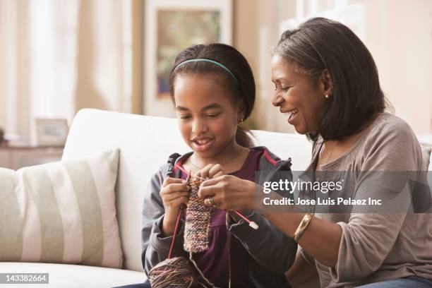 african american grandmother teaching granddaughter how to knit - old granny knitting stock-fotos und bilder