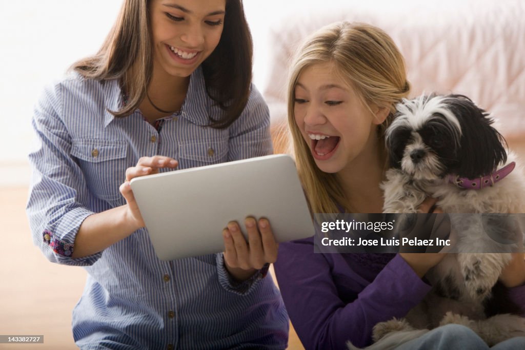 Girls sitting with dog and using digital tablet