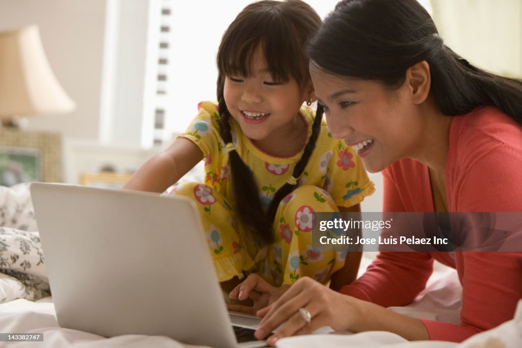 Asian mother and daughter using laptop