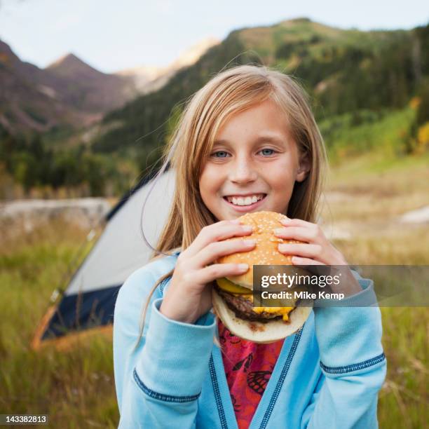 caucasian girl eating cheeseburger at campsite - burger portrait photos et images de collection