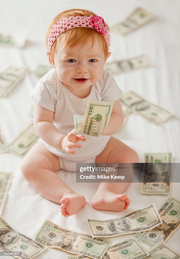 Caucasian baby girl playing with twenty dollar bills