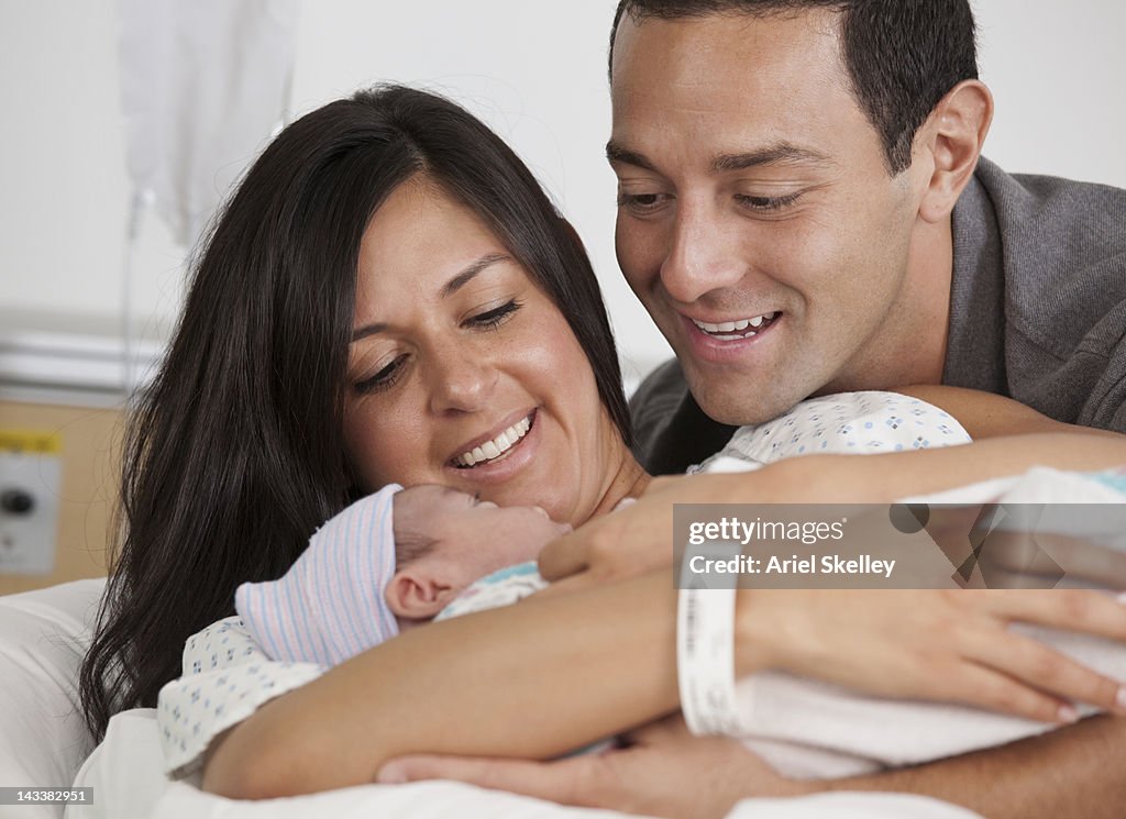 Hispanic parents looking at newborn baby