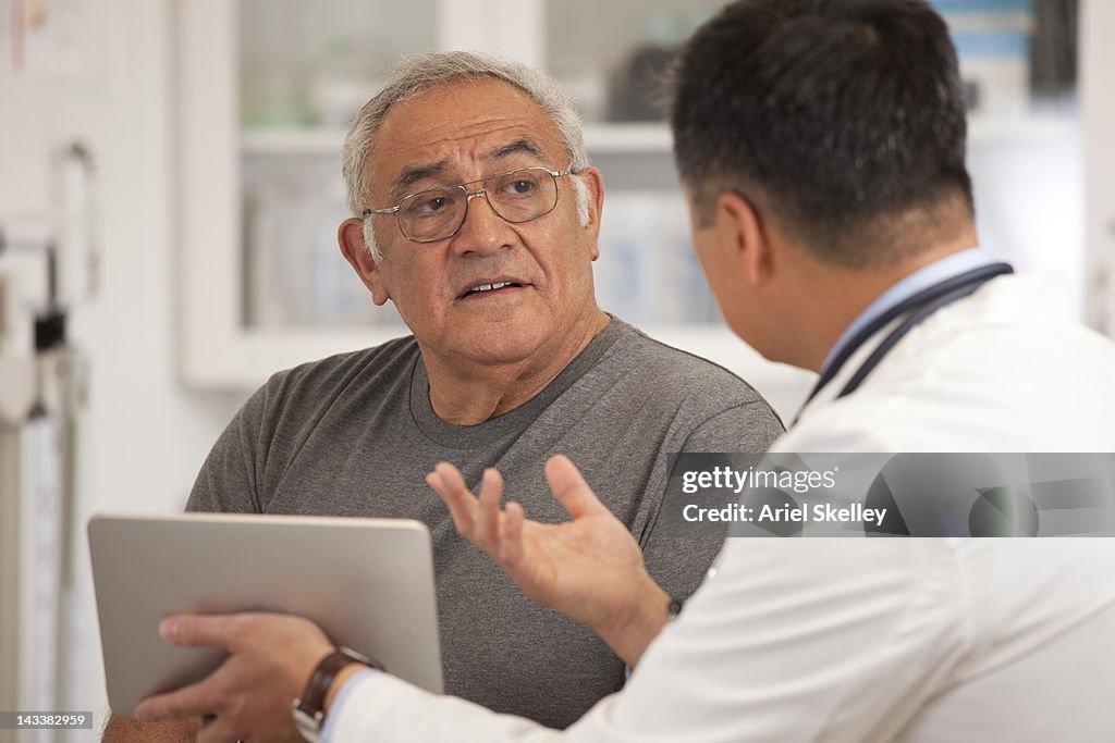 Doctor using digital tablet to talk to senior man