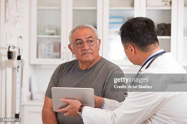 doctor using digital tablet to talk to senior man - hombre revision fotografías e imágenes de stock