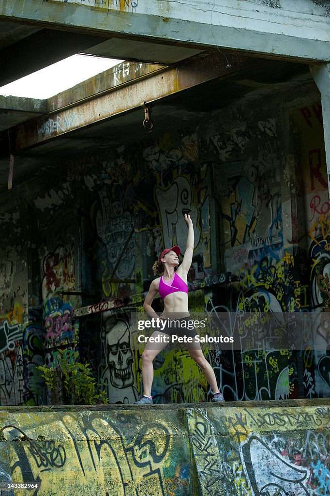 Caucasian woman stretching in abandoned loading dock