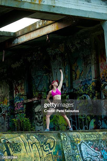 caucasian woman stretching in abandoned loading dock - pete vandal stock pictures, royalty-free photos & images