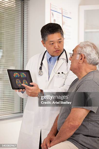 doctor using digital tablet to talk to senior man - neurologist stock pictures, royalty-free photos & images