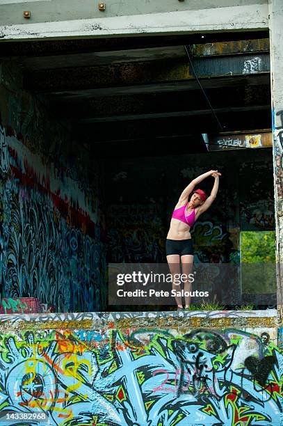 caucasian woman stretching in abandoned loading dock - pete vandal stock-fotos und bilder